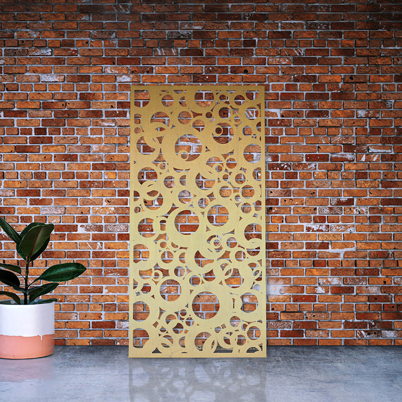 Decorative Privacy screen made from laser cut brass leaning on factory wall