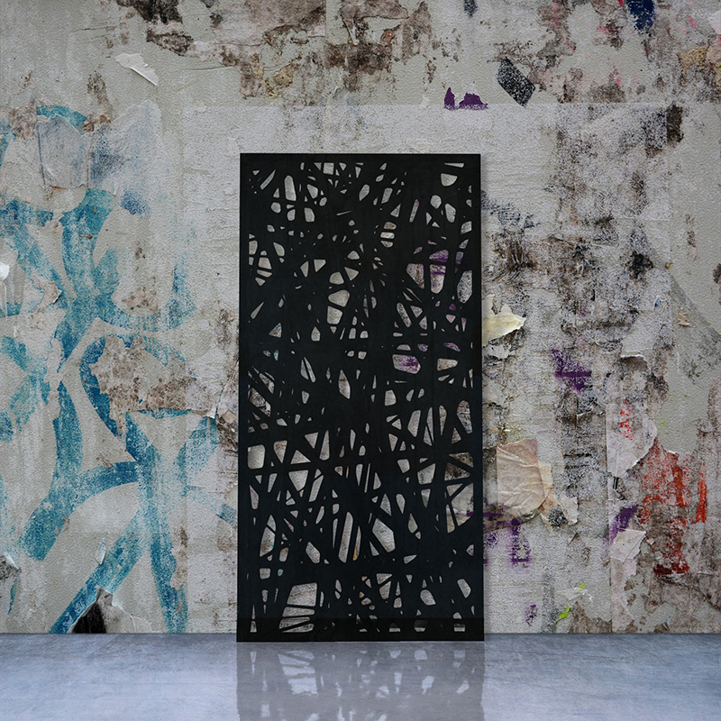 Black Laser Cut Metal Screen leaning on factory wall with torn posters