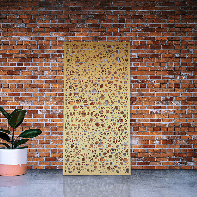 Decorative laser cut garden screen made from brass leaning on factory wall