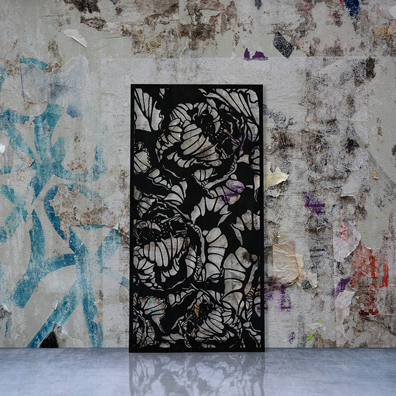 Black laser cut screen with Peony design leaning on factory wall
