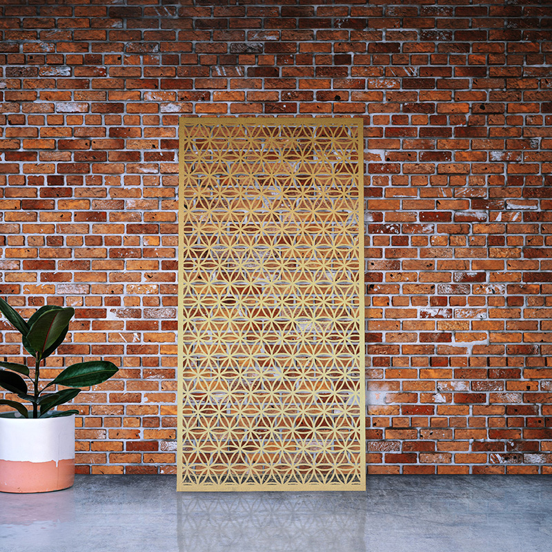 Laser cut brass screen leaning on red brick factory wall