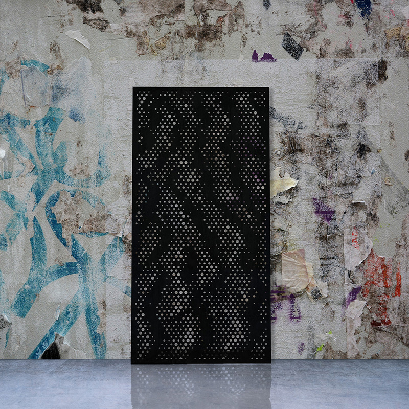 Laser Cut Black Metal Screen leaning on a factory wall with graffiti and street posters