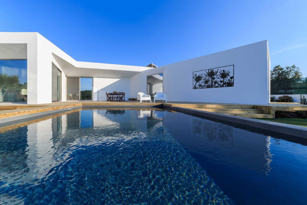 Wall mounted screen positioned over pool in modern landscape and architectural home.