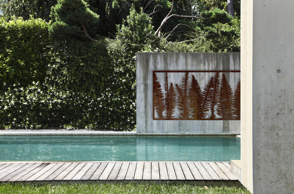 Metal Garden Screen used as artwork displayed on wall over pool in modern landscape