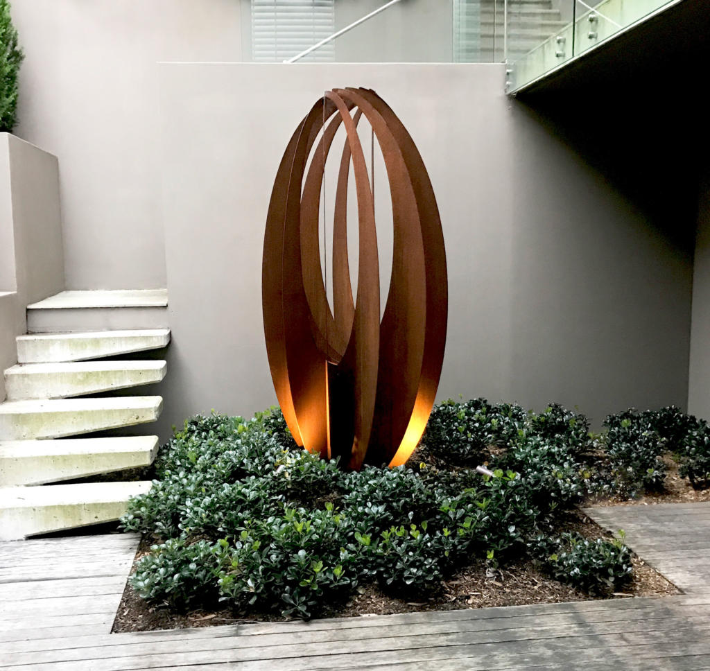 Steel Rusted Sculpture made from Corten steel by Lump Studio placed in the garden at a modern home