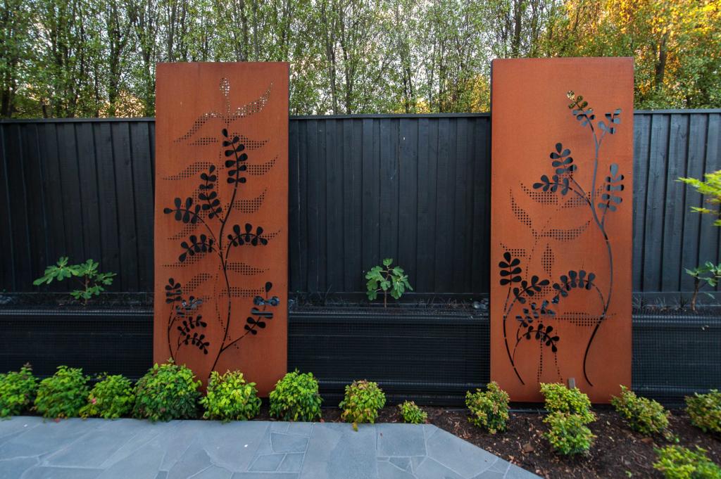 Corten steel screens with rusted finish and laser cut design in garden