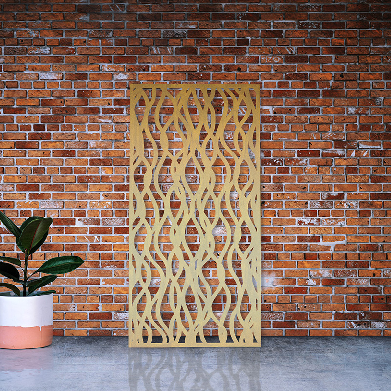Decorative laser cut garden screen made from brass leaning on factory wall