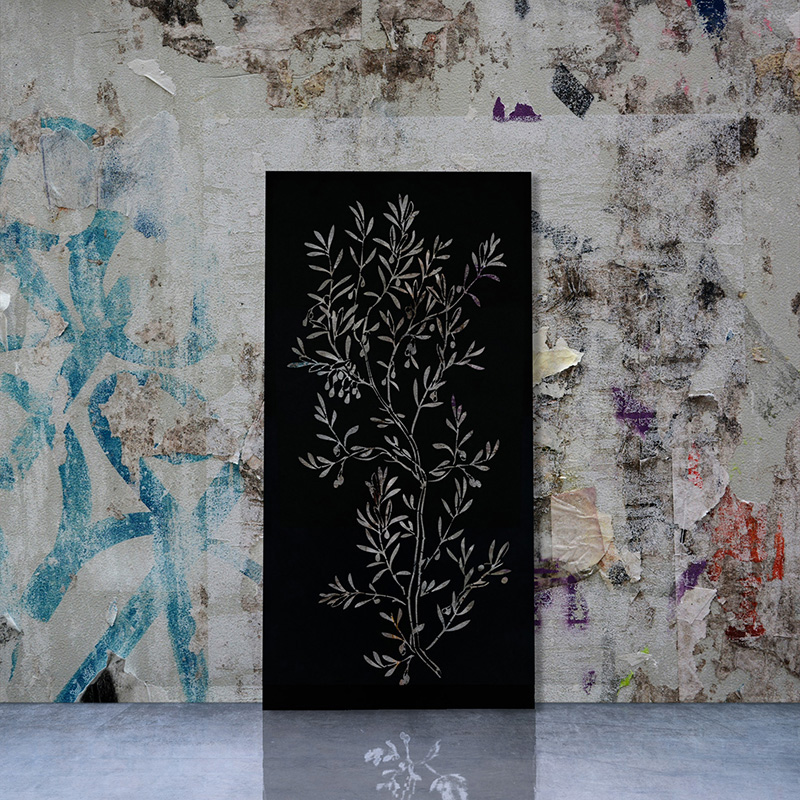 Black metal garden screen with laser cut screen design leaning on factory wall