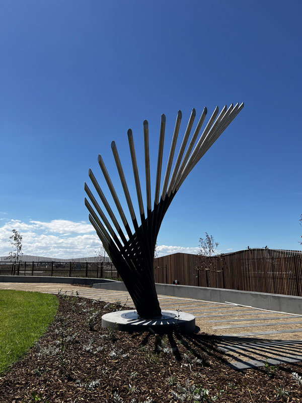 Tall stainless steel and black sculpture by Lump Studio depicting the wing of a bird.