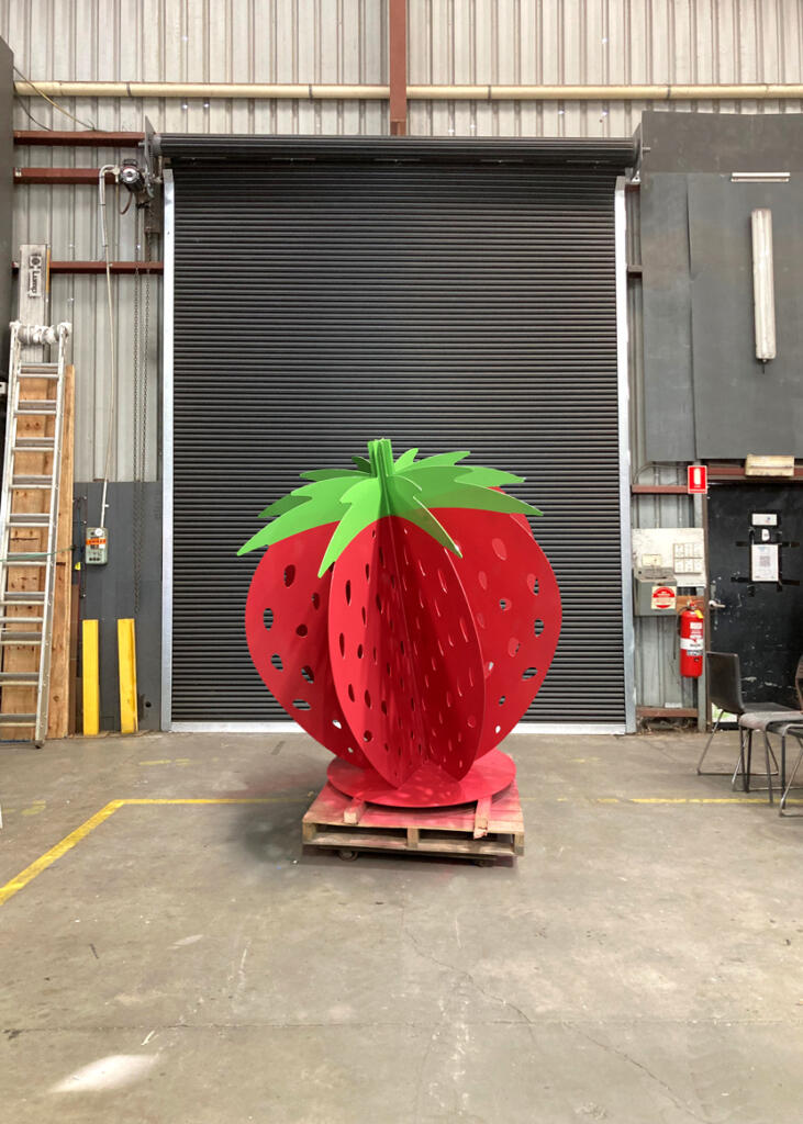Large red strawberry sculpture at Yarra Farm Fresh, created by Lump Sculpture Studio, serving as a photo landmark for visitors.
