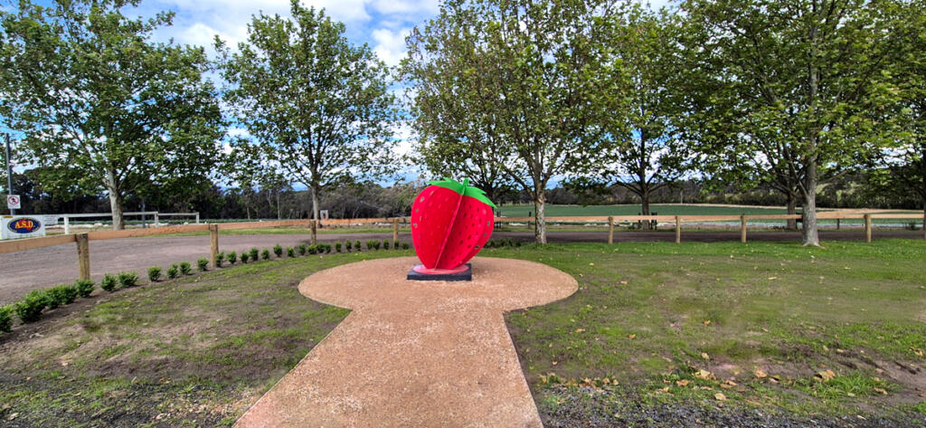 Large red strawberry sculpture at Yarra Farm Fresh, created by Lump Sculpture Studio, serving as a photo landmark for visitors.