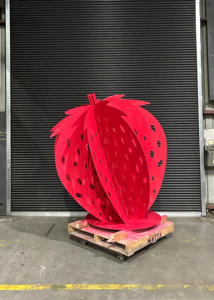 Large red strawberry sculpture at Yarra Farm Fresh, created by Lump Sculpture Studio, serving as a photo landmark for visitors.