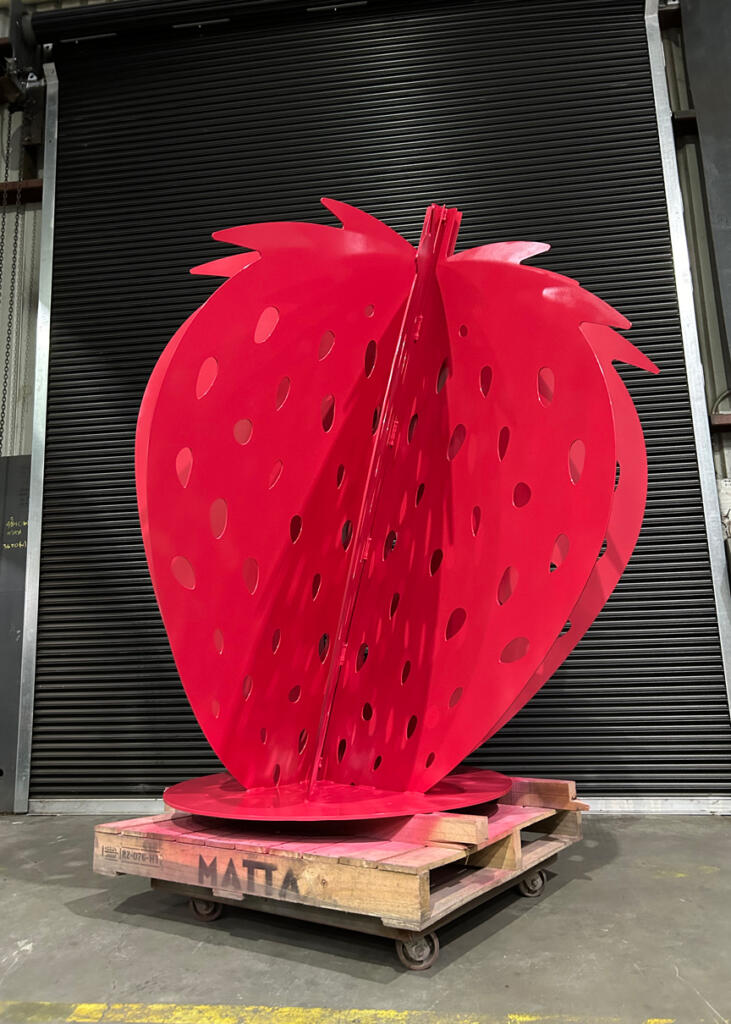 Large red strawberry sculpture at Yarra Farm Fresh, created by Lump Sculpture Studio, serving as a photo landmark for visitors.