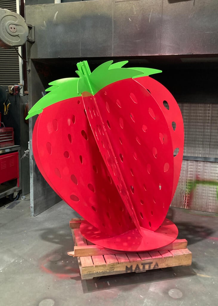 Large red strawberry sculpture at Yarra Farm Fresh, created by Lump Sculpture Studio, serving as a photo landmark for visitors.