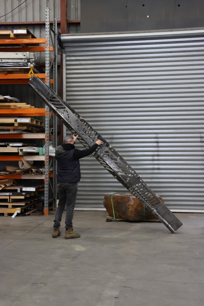 Corten steel and stainless steel canoe sculpture by First Nations artist Simone Thomson, fabricated by Lump Studio, installed on natural rock in Port Melbourne.