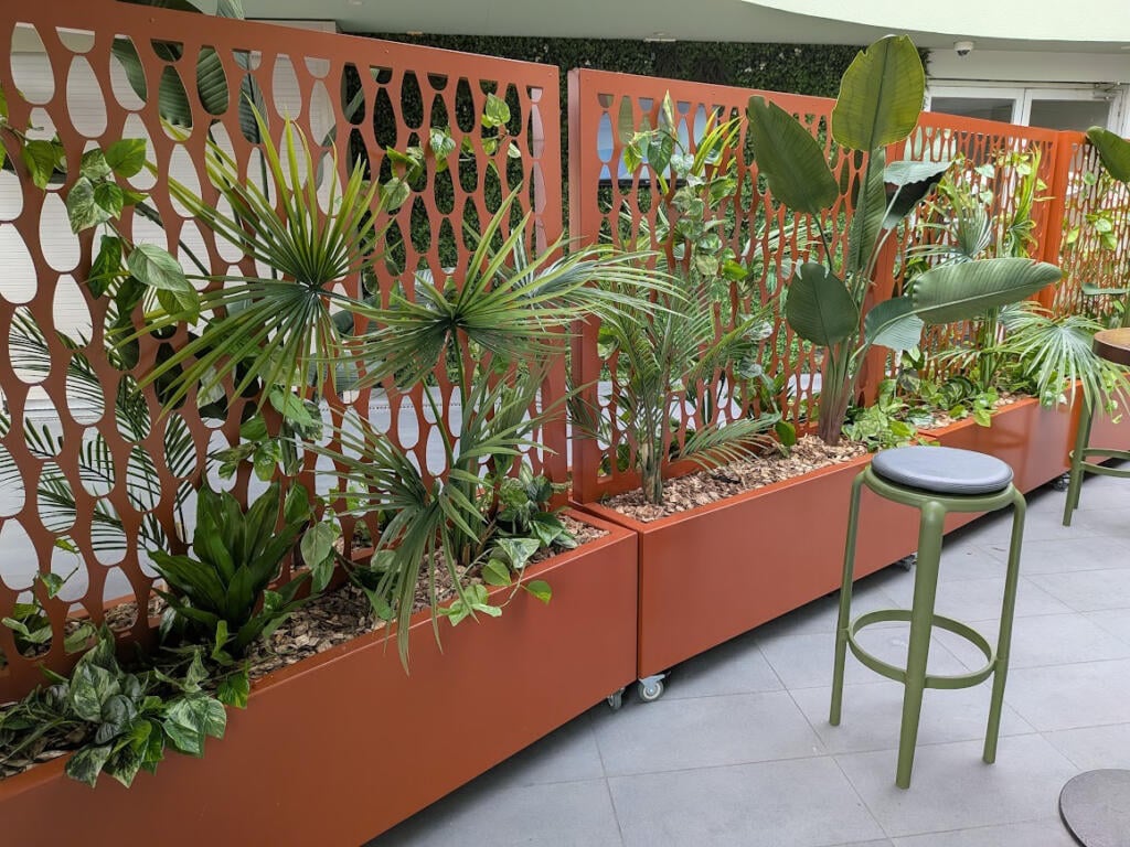 Custom Corten steel planter with drop-in pot system allowing individual potted native plants to be easily removed and replaced.