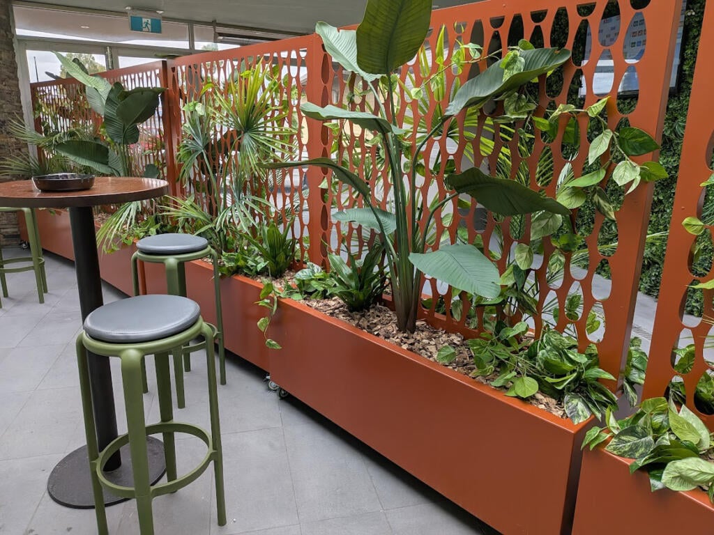Custom Corten steel planter with drop-in pot system allowing individual potted native plants to be easily removed and replaced.